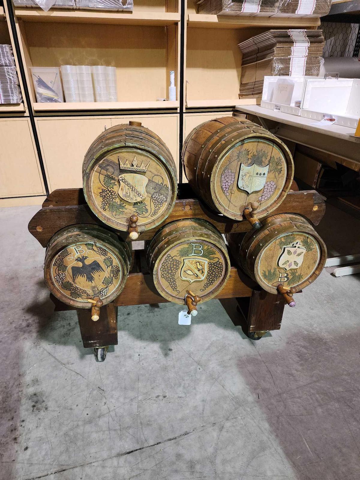 Five wooden Bavarian style 5 gal beer barrels with stand on wheels. Two racks, one holds three