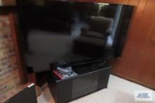 Vizio model number E65-EZ065-in flat screen TV on stand with accessories and remotes