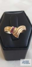 Gold colored v-shaped ring with pinkish purple stone, marked 14K, total approximate weight is 2.75 G