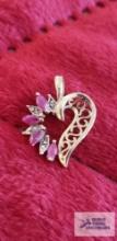 Gold colored heart-shaped pendant with clear and pinkish purple gemstones, marked 10K, approximate