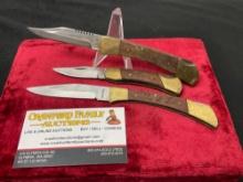 Trio of Three Folding Knives, in the style of classic Buck knives, Wood & Brass