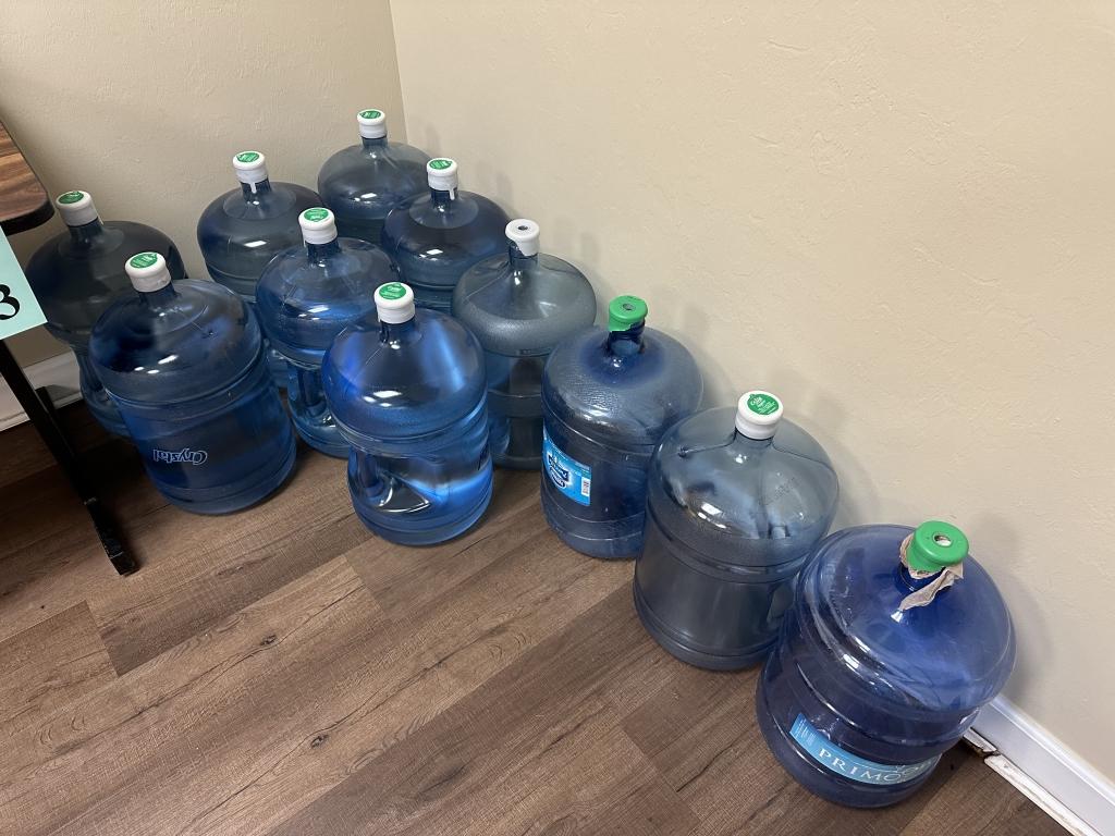 WATER COOLER WITH (7) FULL AND (4) EMPTY JUGS