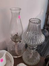 (LR) LOT OF (2) VINTAGE CLEAR GLASS OIL LAMPS WITH CHIMNEYS. ONE DEPICTS A HORSE AND BUGGY AT THE